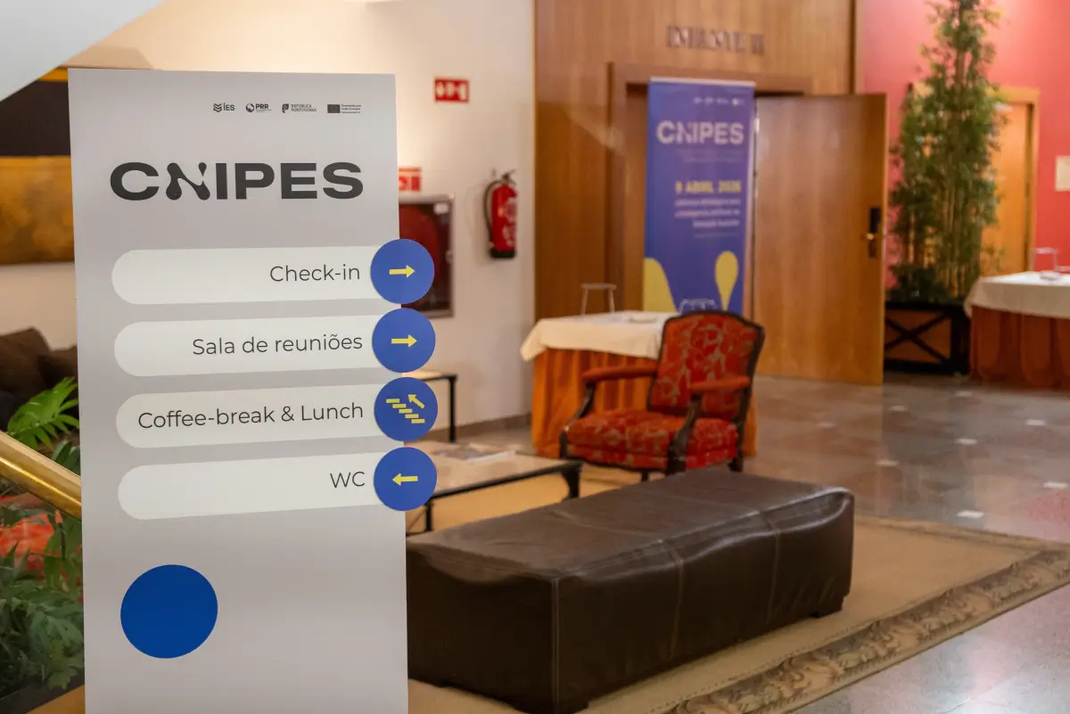 Sinalética do CNIPES com indicações para check-in, sala de reuniões, coffee-break, almoço e WC durante um evento institucional.
