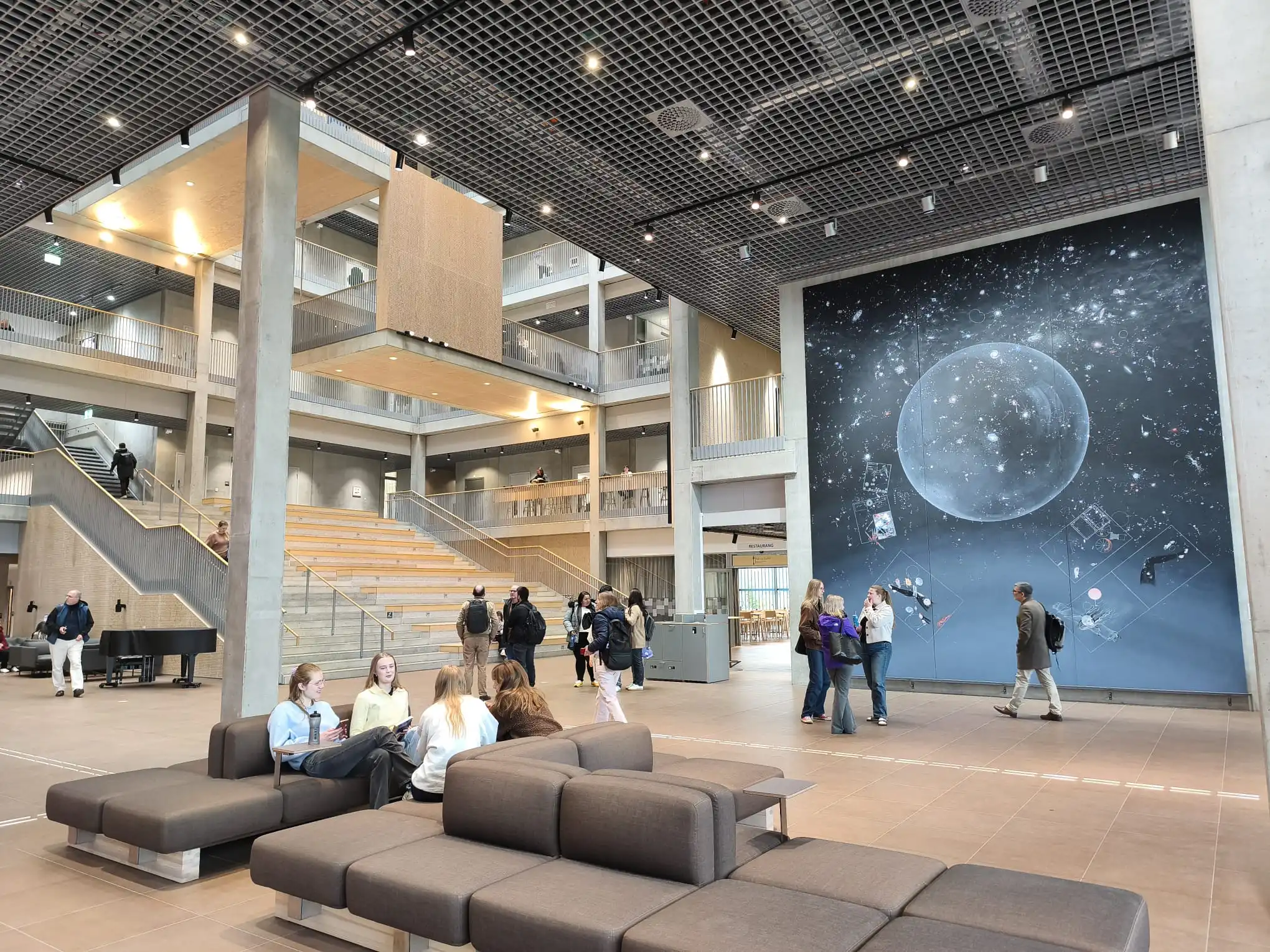 Interior de um edifício moderno, com participantes a circular num espaço amplo e iluminado.