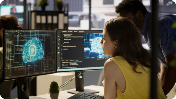 Duas pessoas analisam ecrãs com código e visualização de inteligência artificial.