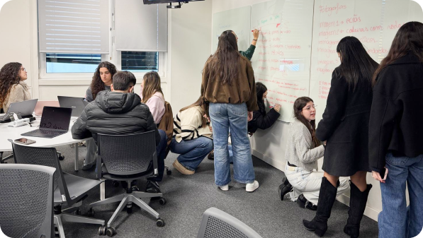 Grupo de participantes a desenvolver uma atividade colaborativa junto a um quadro branco.