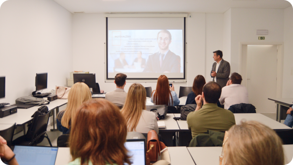 Sessão em sala de aula com participantes a assistir a uma apresentação projetada no ecrã.