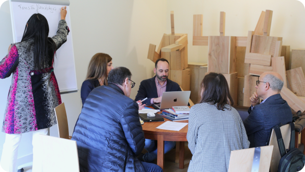 Reunião de trabalho com participantes sentados à volta de uma mesa, em contexto institucional ou académico.